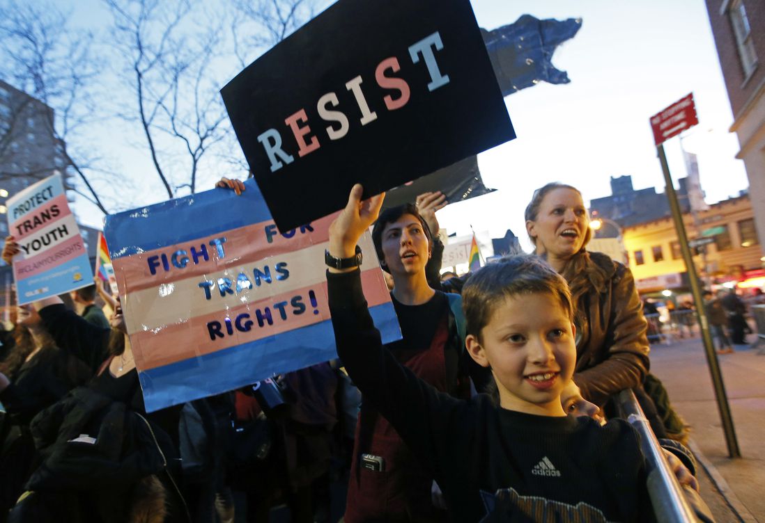 Tal Moskowitz, 8, below, a transgender child, holds a sign as his parents Faigy Gelbstein, left, and Naomi Moskowitz, upper right, of Long Island, hold separate signs during a rally in support of transgender youth at the Stonewall National Monument, Thursday, Feb. 23, 2017 (Kathy Willens / AP)
